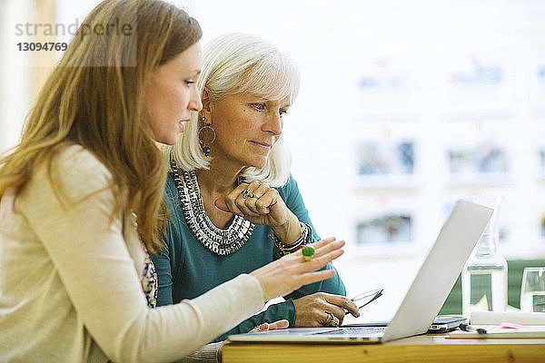 Weibliche Mitarbeiter recherchieren am Laptop-Computer im Sitzungssaal