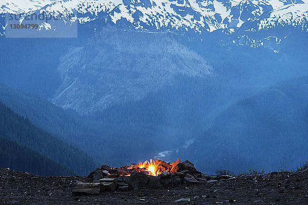 Lagerfeuer auf dem Feld gegen schneebedeckte Berge