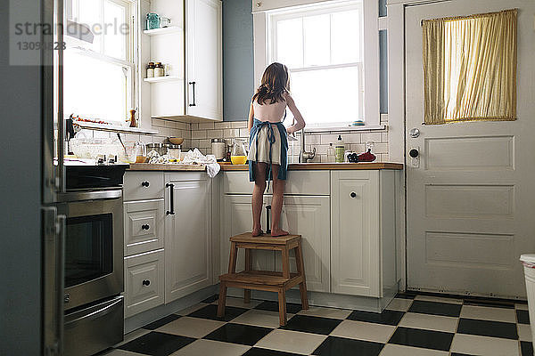 Rückansicht eines Mädchens  das zu Hause in der Küche Geschirr spült