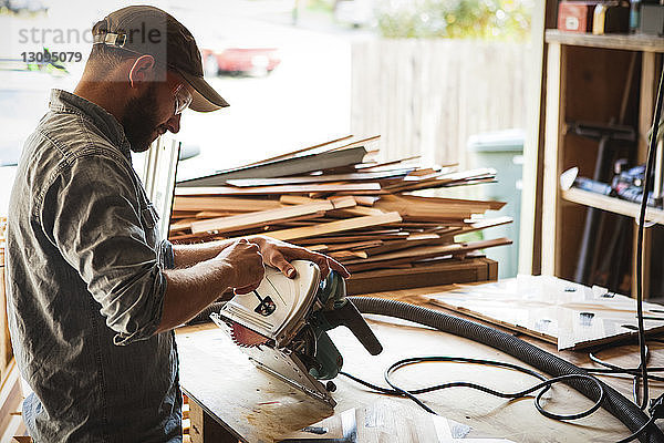 Handwerker  der die Kreissäge bei der Arbeit in der Werkstatt überprüft