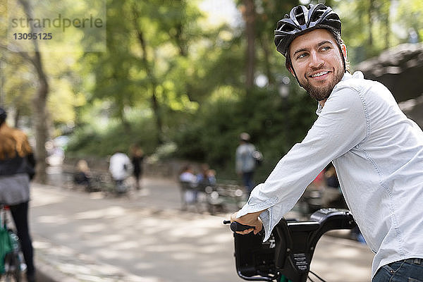 Mann schaut weg  während er mit seiner Freundin im Park Fahrrad fährt