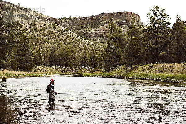 Seitenansicht eines erwachsenen Mannes beim Fischen im Fluss am Berg