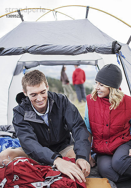 Glückliche Frau schaut den Mann an  während sie im Zelt sitzt