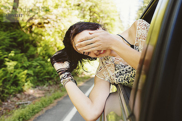 Glückliche Frau  die während der Fahrt im Auto durchs Fenster schaut
