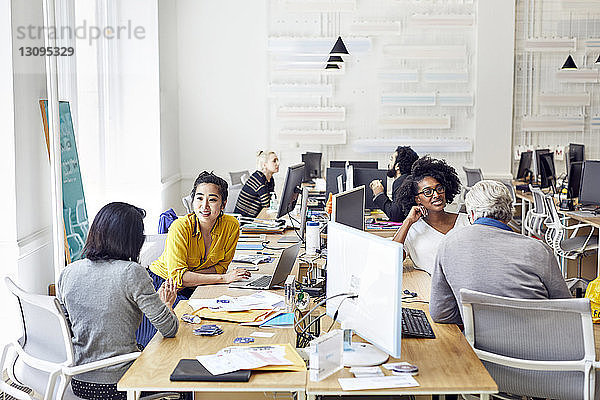 Hoher Blickwinkel auf Geschäftsleute  die während der Arbeit im Kreativbüro sprechen