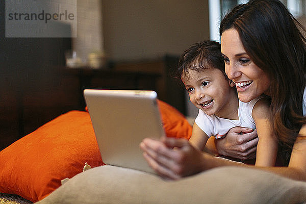 Glückliche Mutter mit Tochter schaut auf Tablet-Computer