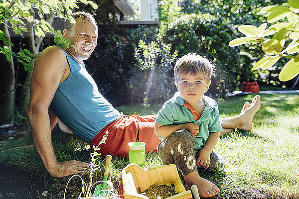 Porträt eines Jungen  der mit seinem Vater im Garten sitzt