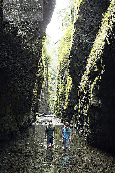 Paar beim Wandern im Bach inmitten von Felsformationen