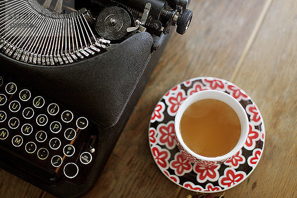 Draufsicht auf Schreibmaschine und Tee auf Holztisch