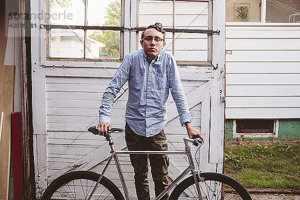 Porträt eines Mannes mit Fahrrad vor einer Garagentür stehend