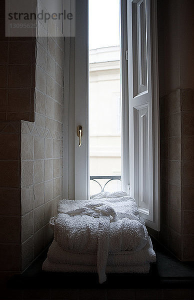 Auf die Fensterbank gestapelte Bademäntel im Badezimmer