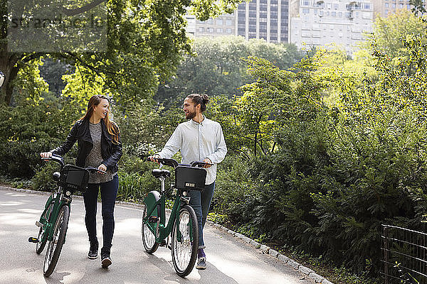 Paar redet während des Gehens auf einem Fußweg mit Fahrrädern