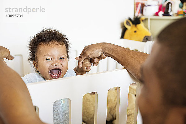 Porträt eines fröhlichen kleinen Jungen  der mit seinem Vater zu Hause spielt