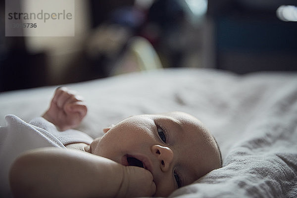 Porträt eines kleinen Jungen  der zu Hause auf dem Bett liegt