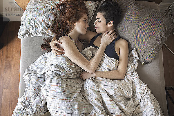Hochwinkelansicht eines romantischen lesbischen Paares  das sich im Bett betrachtet