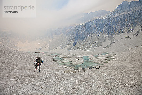 Rückansicht eines Wanderers  der auf dem Gletscher geht  gegen den Himmel