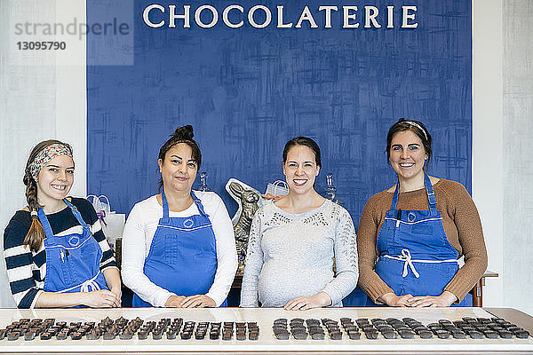 Porträt weiblicher Mitarbeiter  die bei Tafelschokolade im Laden stehen