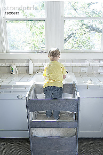 Rückansicht eines Jungen  der zu Hause am Badezimmer-Waschbecken steht