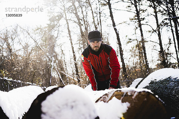 Niedrigwinkelansicht eines Arbeiters  der an schneebedeckten umgestürzten Bäumen im Hinterhof steht