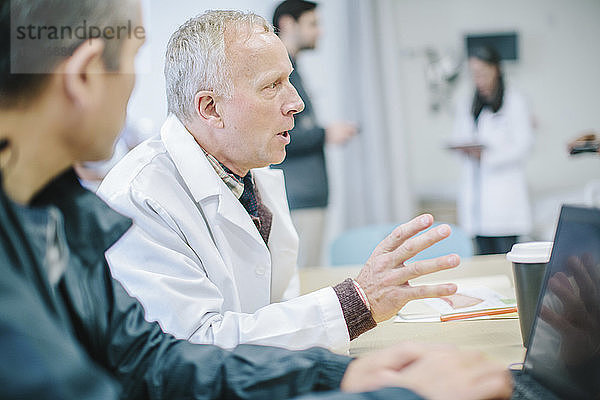 Ärzte diskutieren am Tisch im medizinischen Raum des Krankenhauses