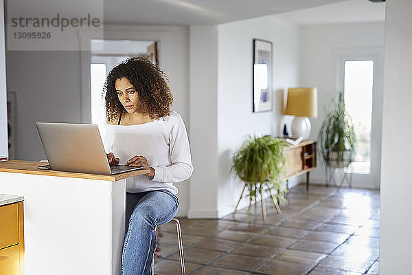 Frau benutzt Laptop-Computer auf dem Tisch zu Hause