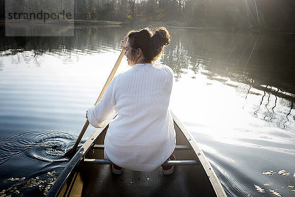 Rückansicht einer Frau  die in einem Boot auf einem See im Wald sitzt