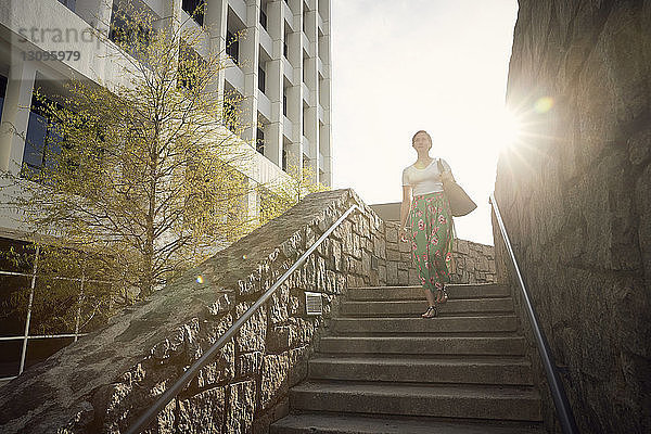 Niedrigwinkelansicht einer Frau  die sich an einem sonnigen Tag auf Stufen gegen den Himmel bewegt