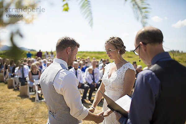 Junges Paar heiratet bei Sonnenschein von Priester