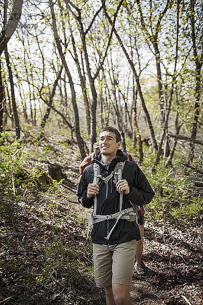 Glücklicher Mann mit Rucksack beim Wandern im Wald