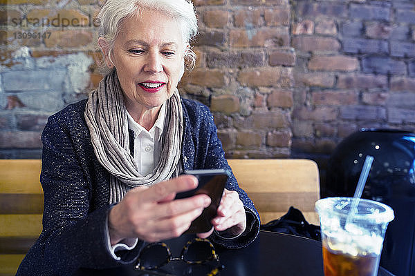 Ältere Frau benutzt Smartphone im Straßencafé