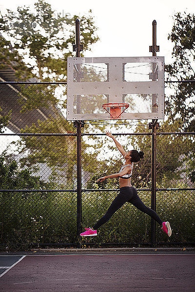 Sportliche Frau erreicht Basketballkorb
