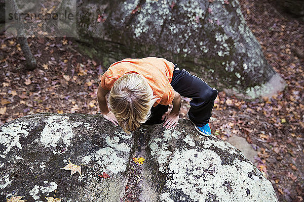 Junge klettert Felsbrocken im Wald