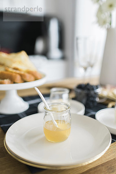 Hochwinkelansicht von Honig in einem Glas mit Tellern auf dem Tisch