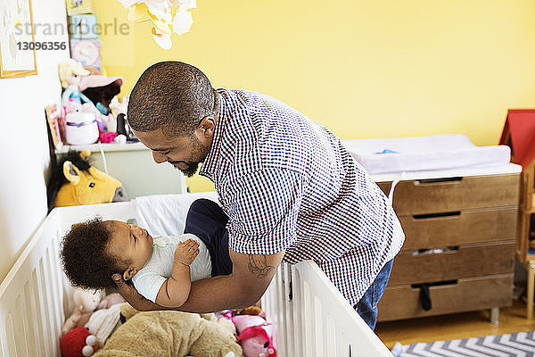 Glücklicher Vater legt Sohn zu Hause ins Kinderbett