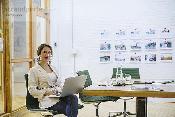 Porträt einer lächelnden Geschäftsfrau mit Laptop-Computer im Sitzungssaal