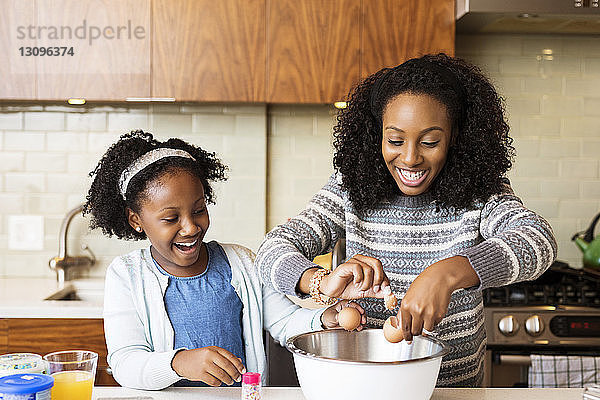 Glückliche Mutter und Tochter backen Cupcakes in der Küche