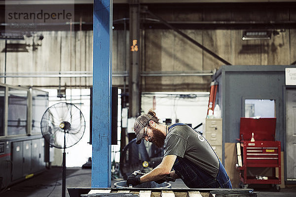 Seitenansicht eines Arbeiters mit Hammer und Meißel in einer Stahlfabrik