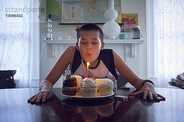 Teenager-Mädchen bläst zu Hause Geburtstagskerze auf dem Tisch aus
