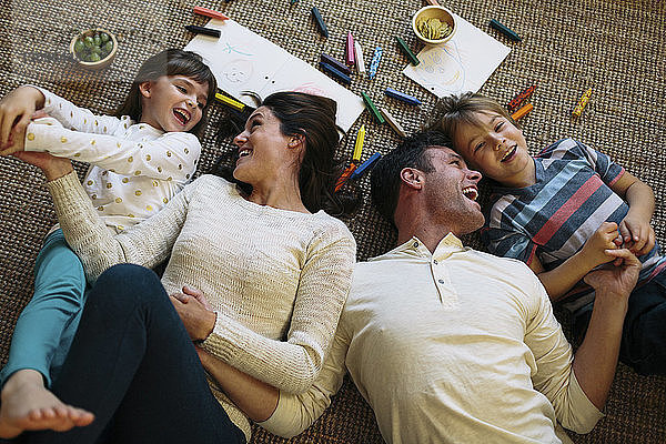 Draufsicht auf glückliche Eltern mit Kindern  die zu Hause auf einem Teppich liegen