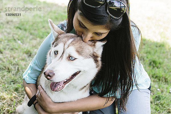 Hochwinkelaufnahme einer Frau  die einen Hund im Park umarmt
