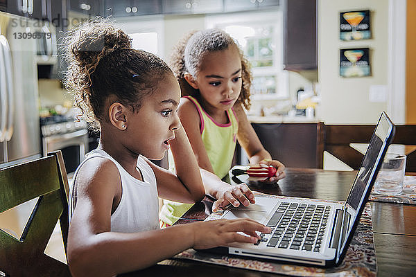 Süße Mädchen benutzen zu Hause einen Laptop