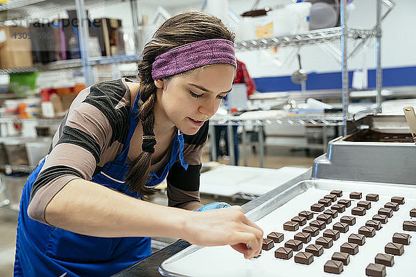 Köchin arrangiert Schokoladenstücke in der Fabrik in einem Tablett