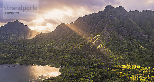 Idyllischer Blick auf die Berge am See gegen den bewölkten Himmel bei Sonnenuntergang