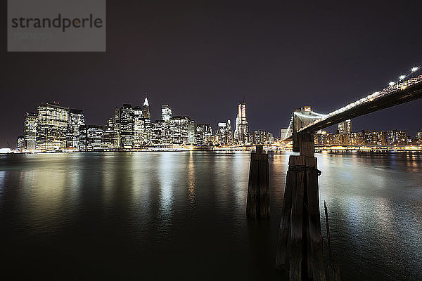 Beleuchtete Brooklyn Bridge über den East River mit der Stadt im Hintergrund