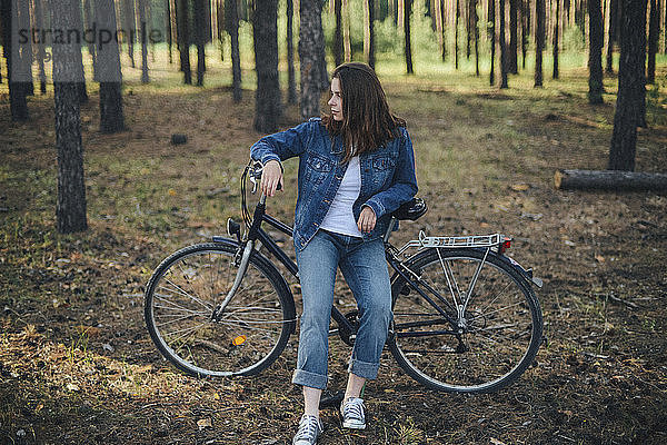 Frau schaut weg  während sie mit dem Fahrrad im Wald sitzt