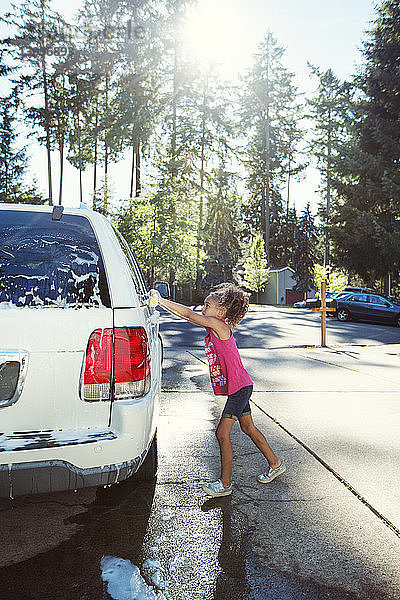 Seitenansicht eines Mädchens beim Autowaschen in der Einfahrt