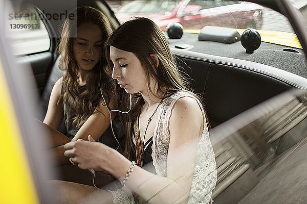 Freundinnen  die während einer Taxifahrt Musik hören