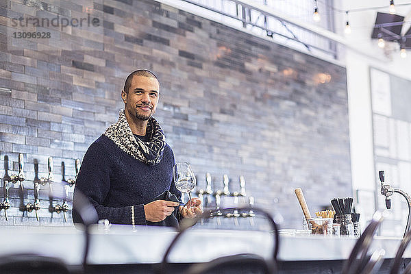 Barkeeper schaut weg  während er Weinglas an der Bartheke im Restaurant hält