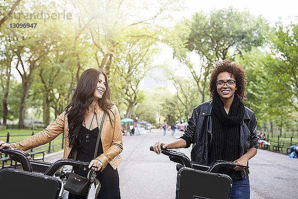 Glückliche Freunde unterhalten sich beim Spaziergang mit dem Fahrrad auf dem Fußweg