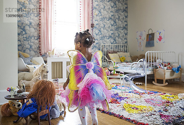 Rückansicht eines im Feenkostüm gekleideten Mädchens  das im Schlafzimmer geht